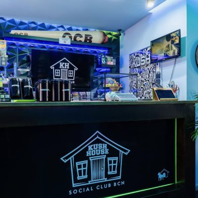 Bar v Kush House Social Club, nasvícený modře, s logem klubu na přední straně baru.